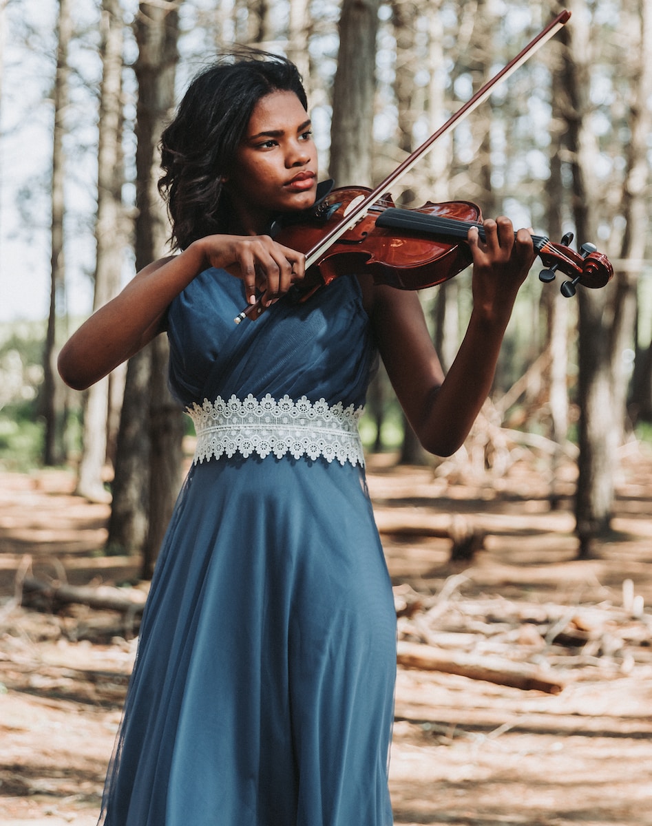 a woman in a blue dress playing a violin